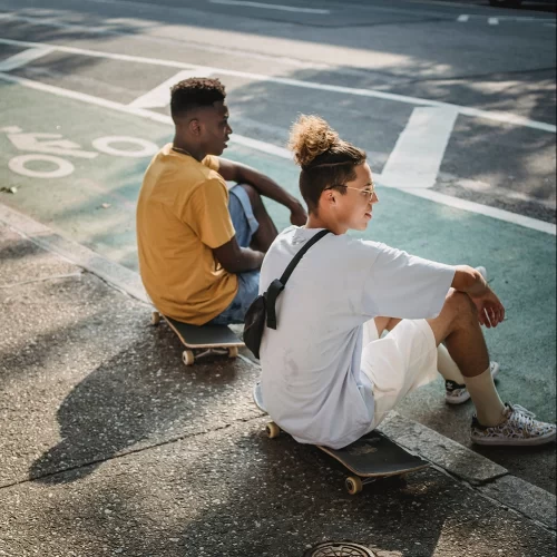 Two young men sitting on their skateboards at the park